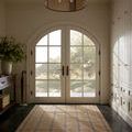 Judy Natural / Stone Rug placed in a bright entryway with arched double doors and tile flooring