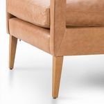 Close-up of the chair’s tapered oak leg and leather frame corner