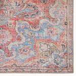 Close-up top-down of rug detailed floral corner design featuring worn red and blue patterns