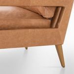 Close-up of chair's lower side revealing leather upholstery meeting tapered oak leg