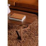 Close-up angled view of walnut table top with stacked books on thick shaggy brown carpet
