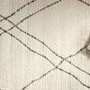 Detailed look at rug surface with charcoal lines and styled with glasses and books on top