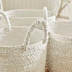 Close-up of multiple Madura Market basket handles against a natural fiber rug background
