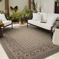 Charcoal rug placed outdoors on patio under white cushioned metal-frame seating surrounding it