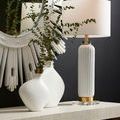 Console table with white ceramic lamp, sculptural white vases, and mirrored circular sunburst wall decor