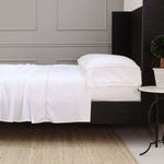 Set of two standard-size Sheena Bamboo Sateen pillowcases in warm sand tone on a bed with black frame