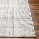 Detailed border corner close-up of Sammy rug on medium-tone wood flooring highlighting pattern and weave