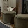 Two olive velvet ottomans in front of fireplace with basket in cozy room setting