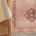 Close-up corner view of rug showing pattern beneath wooden desk with light wood and gray flooring