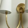 Angle showing sconce’s brass backplate with ring detail behind fabric shades