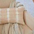Throw loosely draped over cream armchair with beige and white tie-dye pillow