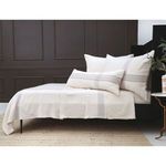 Full side view of Geneva Blanket set on platform bed against dark paneled wall with woven rug