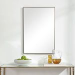 Straight-on view of Owen Mirror in room setting with decorative bowl and glass pitcher on console