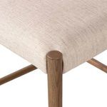 Close-up showing upholstery fabric stretched over rounded wooden seat corners