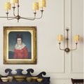 Decorative interior featuring the sconce hung lit beside a traditional chandelier with cut-out shades