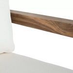 Close-up of teak wood armrest and edge of white seat cushion with fabric texture visible