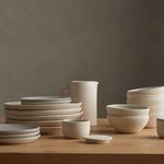 Salt jar among a full set of assorted cream ceramic kitchenware on wooden surface