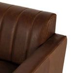 Corner close-up showing leather-wrapped armrest and seat cushion edge with wooden leg beneath.