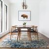 Rug under mid-century modern dining table with wooden chairs in bright room