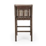 Wilmington Stool positioned on beige rug next to black dining table with decorative vase and bowl