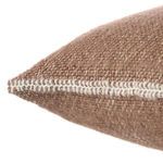 Close-up of pillow corner with thick white stitching detail on brown woven fabric