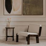 Upright chair with side table and roses in a vase beside abstract framed art in muted home interior