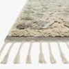 Close-up of taupe smoke shag rug corner showing thick pile and tassel fringe detail