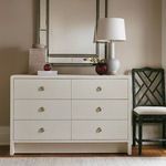 Dining room setting showing the chair beside a six-drawer dresser with a mirror, lamp, and decor
