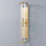Close-up of brushed brass bottom frame curl and clear ribbed glass shade with lit bulb