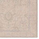 Detailed close-up of rug border showcasing delicate beige, light blue, sage, and brown medallion design