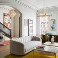 Living room scene with the chandelier visible above a gray sofa and colorful abstract painting