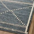 Angled top view of rug on wood floor focusing on diamond motif and raised cream borders