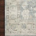 Close-up of the Rosette Denim / Fog rug corner showing its intricate border against dark hardwood floor