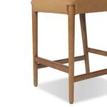 Close-up of the bottom corner of the stool showing wooden leg and connecting supports