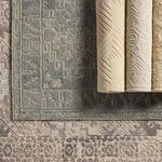 Rolled beige and cream rugs with various tribal and geometric patterns stacked on top of each other