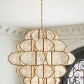 Chandelier hanging in bright room corner with decorative molding and arched window