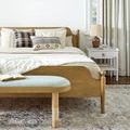 Doheny End Table styled in a bedroom room setting beside a wooden bed with pillows and a lamp on the table