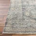 Close-up of rug edge showing fringe detail and intricate border pattern on wood floor