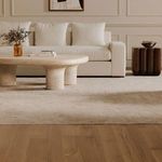 Closer angle showing the sofa with a beige coffee table on a textured rug and a dark wood side table nearby