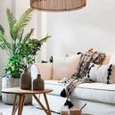 Stain grey/brown vase and smaller matching vase on wooden table in bright living room with white sofa and green plants