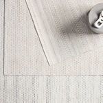 Layered rugs with cream and light gray tribal patterns, showing edges and a decorative object on top