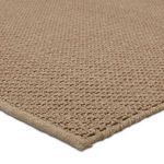 Close-up of thick brown woven texture and finished edge of the rug