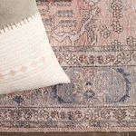 Close-up detail of rug and corner of stitched pink-accented decorative pillows with tassels