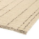 Angled view of rug corner displaying slight pile height and textured vertical stripe pattern