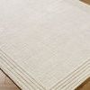 Close-up angle showing the rug’s hand-tufted texture and striped border detail on wooden floor