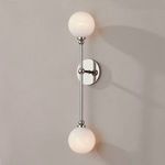 Two-light wall sconce lit with warmer light glow mounted on gray wall casting distinct shadows