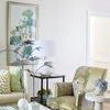 Conner Cane End Table shown in a living room corner next to patterned armchair and decorated with a white lamp