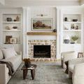 Living room with Jules Emerald rug centered in front of stone fireplace and white built-in shelves