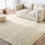 Tallwood area rug styled in a bright living room with beige sofa, pouf, and knit throw over hardwood floor