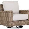 Outdoor swivel club rocker chair with weathered tobacco wicker frame and thick off-white seat and back cushions